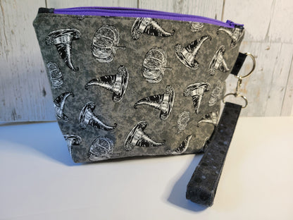 Pouch with witch hat pattern and purple zipper on a light wooden background