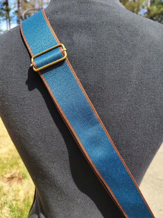 Blue strap with bronze buckle on a blue and brown strap on a black mannequin. 