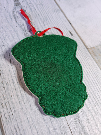 Green felt ornament with a red string on a wooden surface